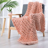 Peach hand knitted weighted blanket draped over chair.